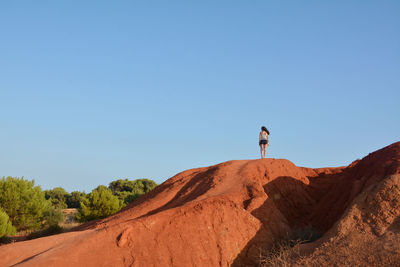 Man standing on rock against clear sky