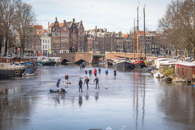 People on river in city against sky