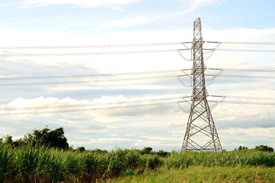 Low angle view of electricity pylon on field against sky