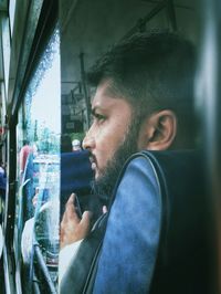 Portrait of young man looking through window