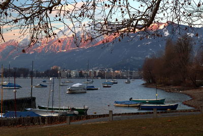 Sailboats moored on lake by mountains against sky