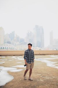 Full length of young man standing against buildings in city