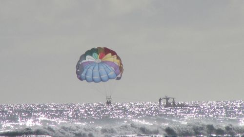 Distant view of people parasailing over sea