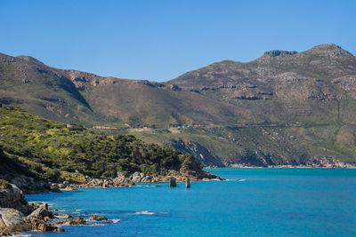 Scenic view of sea and mountains against clear blue sky