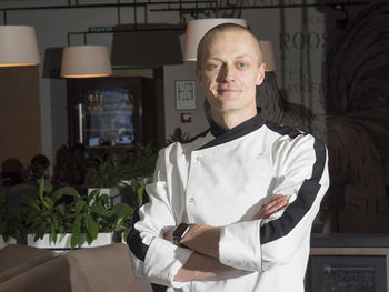 Portrait of confident chef with arms crossed standing at restaurant