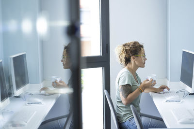 Side view of woman using mobile phone in office