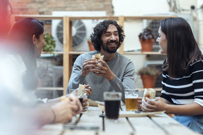 Cheerful businessman and businesswomen having burritos at office cafeteria