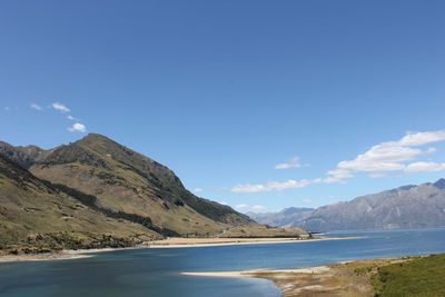 Scenic view of sea and mountains against blue sky