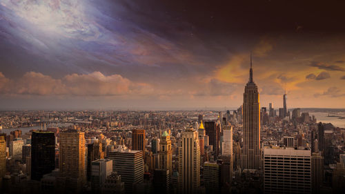 Aerial view of cityscape against cloudy sky during sunset