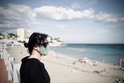 Rear view of man looking at sea against sky