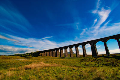 Arch bridge on field against sky