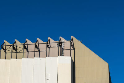 Low angle view of an industrial building against clear blue sky