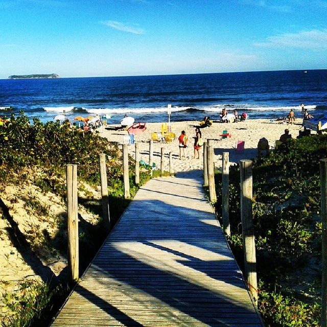 sea, horizon over water, water, beach, railing, blue, tranquility, tranquil scene, beauty in nature, scenics, nature, sky, shore, sunlight, shadow, sand, the way forward, idyllic, boardwalk, incidental people