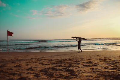 A man with his surfboard walking from the beach