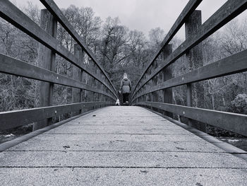 Rear view of woman walking across a wooden bridge