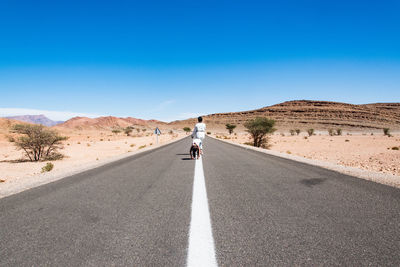 Full length of mother and daughter on road in desert during sunny day