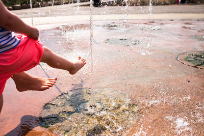 Low section of people with bare feet enjoying in water fountain