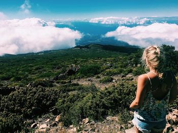 Rear view of woman standing on mountain against sky