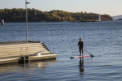 Rear view of man surfing in lake against sky