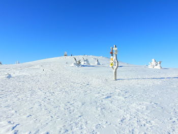 Snow covered land against clear blue sky