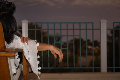 Rear view of woman standing by railing against sky