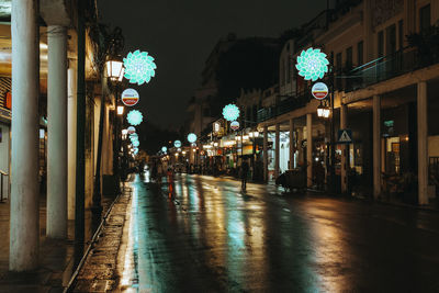 Illuminated street amidst buildings in city at night