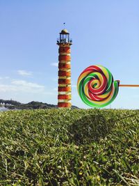 Lighthouse on field against sky