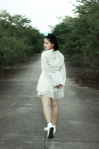 Portrait of young woman standing on road