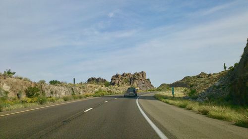 Road leading towards mountain against sky