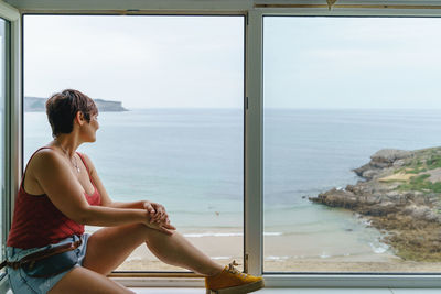 Side view of woman looking at sea against sky