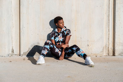 Full length of boy sitting against wall