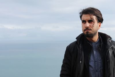 Portrait of young man looking away against sky