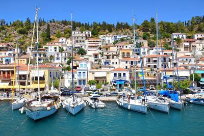 Sailboats moored in harbor by town