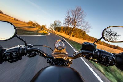 Close-up of motorbike riding on road