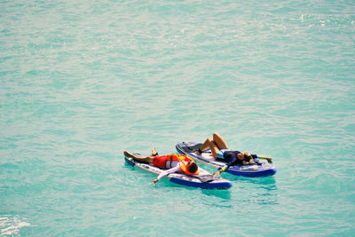 Man and woman lying down on a stand up paddle boards. couple taking time together relaxing on sups