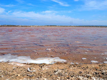 View of calm beach against cloudy sky