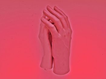 Close-up of artificial hands over pink background