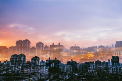 Buildings in city against sky during sunset