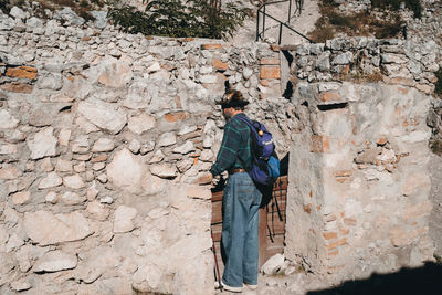 Rear view of woman on rock against wall