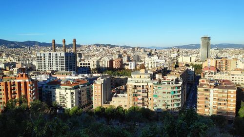 Buildings in city against clear blue sky