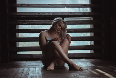 Carefree woman sitting on wooden floor at home