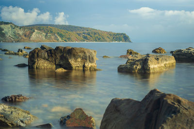 Rocks on sea shore against sky