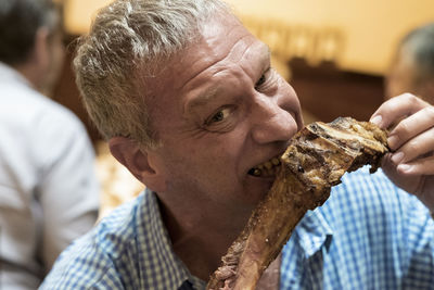 Close-up portrait of man eating meat
