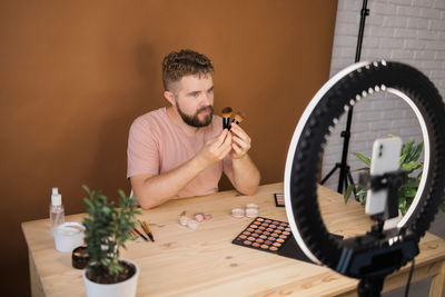 Young man using mobile phone while sitting on table