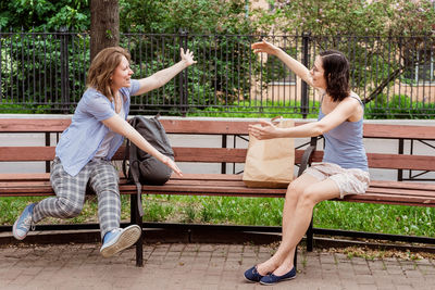 Friends meet each other in the park. greeting girls with social distancing