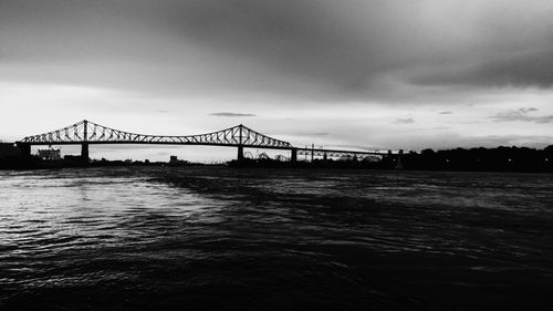 View of suspension bridge over sea against cloudy sky