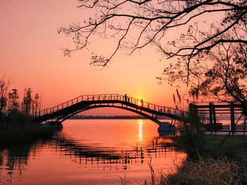 Silhouette of bridge over river at sunset