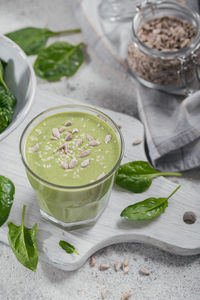 Glass of homemade healthy green smoothie with fresh baby spinach