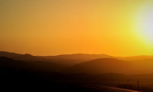 Scenic view of silhouette mountains against clear sky during sunset