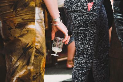 Midsection of woman holding glass while standing outdoors